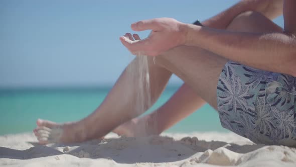 Sand Through Finger.Tanned Man Relaxing Vacation Caribbean Tropical Beach.Summer Sunbathing On Sea.