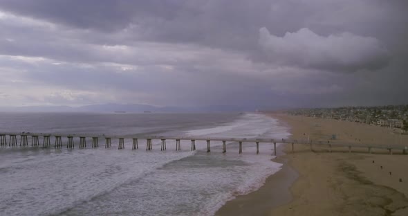 Heavy summer storm waves rolling past the Manhattan Beach Pier in California, AERIAL