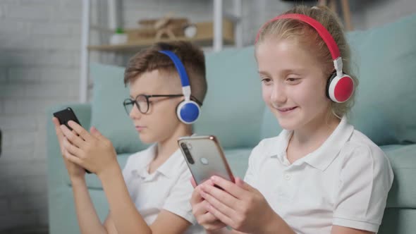 Portrait of Twins Girl and Boy Listening to Music Using Phone and Headphones