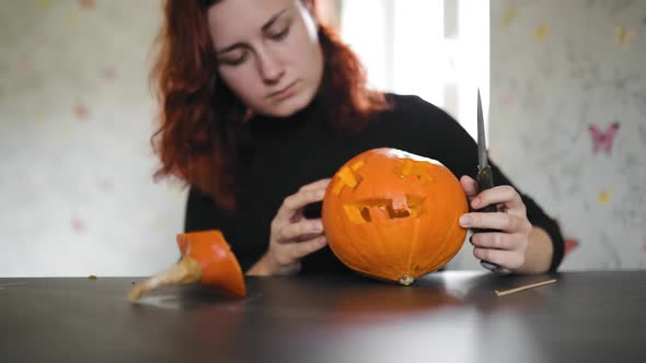 Young Woman Carves Pumpkin on Halloween Eve