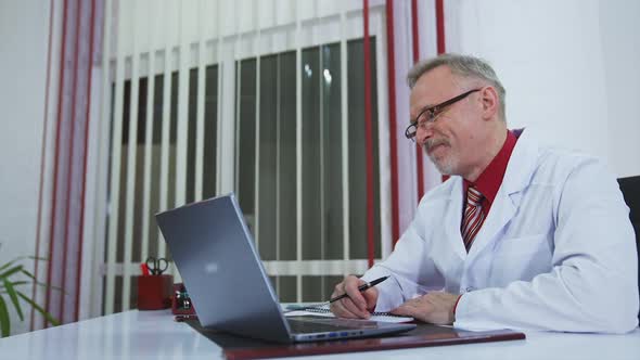 Doctor chatting with patients online, using laptop at his workplace. Telemedicine concept