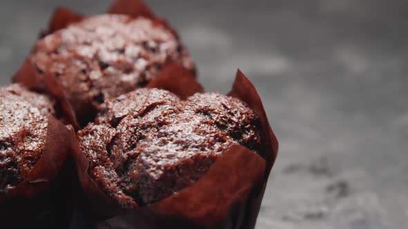 Ready-to-eat сhocolate muffins with crispy top on the gray background.