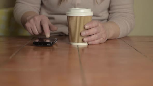 Hands holding a takeaway coffee to-go with phone wide shot