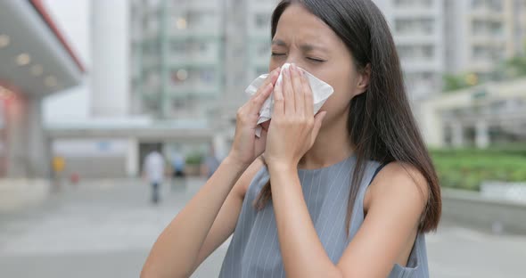 Woman coughing and sneezing at outdoor in the city 