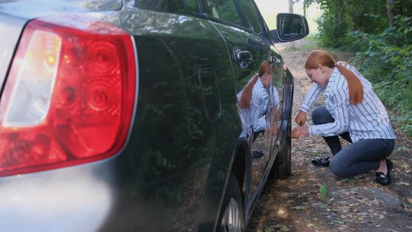 Woman with Wrench Tightening Screws of Automobile Wheel in the Forest. 