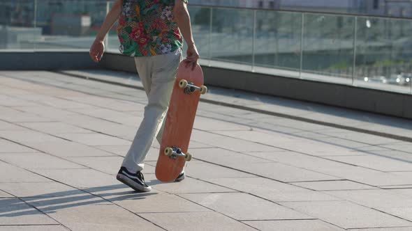 Young Man Picking Up Board While Skating Outdoors