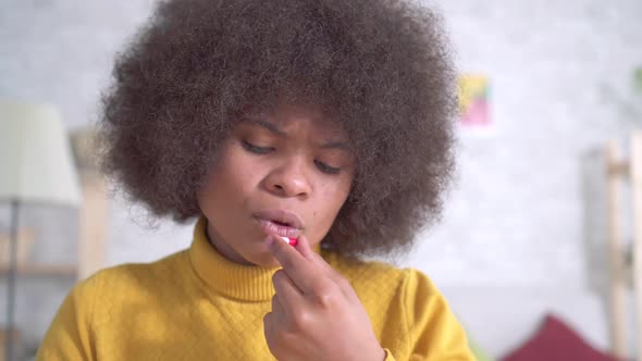 Beautiful African American Woman with an Afro Hairstyle Takes a Pill and Drinks From a Glass of