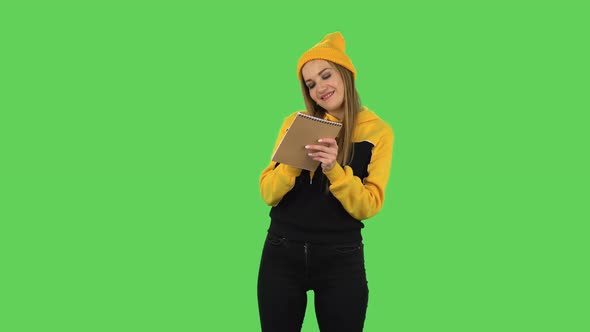 Modern Girl in Yellow Hat Is Standing and Thinking, Then Happy Writing with Pencil in Notebook