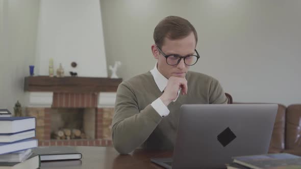 Portrait Adorable Young Man in Glasses Sitting at the Wooden Table in the Office