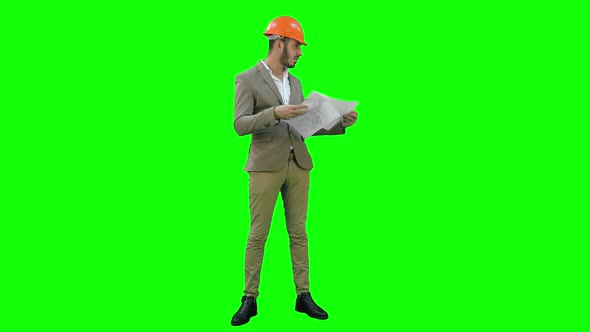 Young Architect in Helmet Checking Construction Plans on a Green Screen, Chroma Key