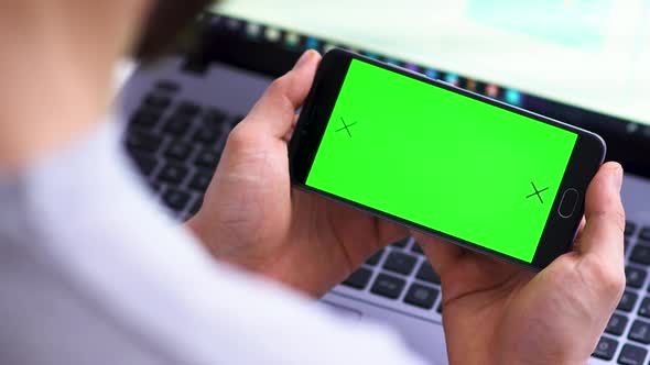 Black Smartphone Horizontally with Green Screen for Chroma Key Compositing the Hands of a Man