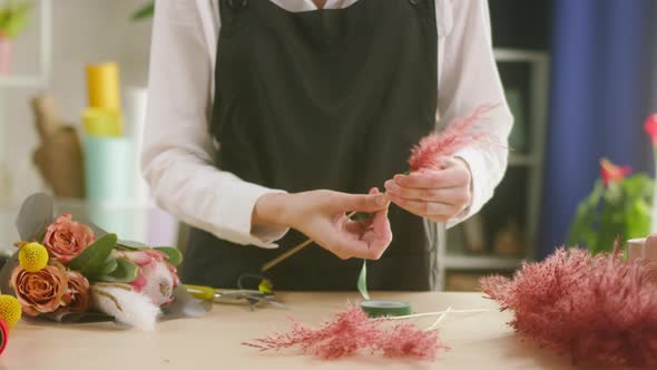 Young Florist Tying Pink Dried Flowers with Ribbon Preparing Details for Making Bouquet at Workplace