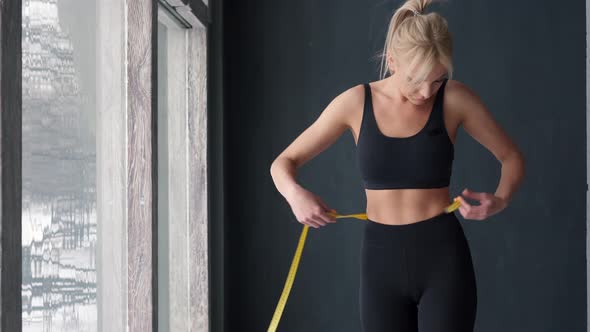 Slim Woman Measuring Waist with Tape Measure in Centimeters