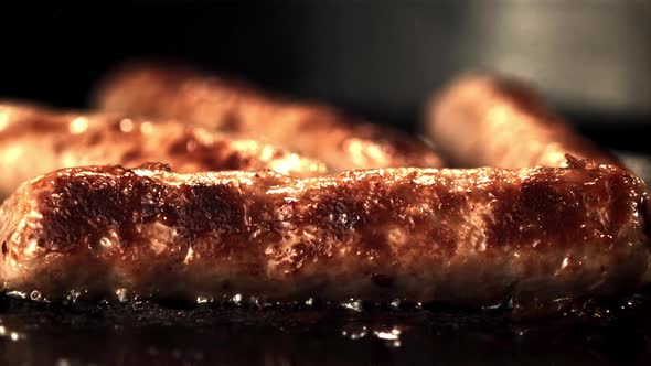 Super Slow Motion Sausages are Fried in a Frying Pan with Splashes of Oil