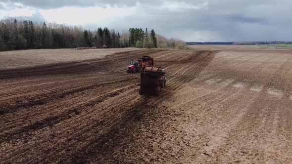 Two Tractors with trailers Spreading Organic Manure on Farm Field