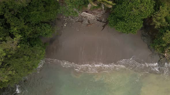 top down view rising drone flight over a sandy beach of a tropical island in the ocean