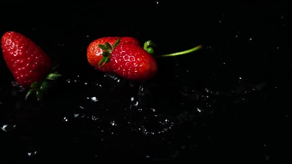 Falling of Strawberry in Water on Black Background