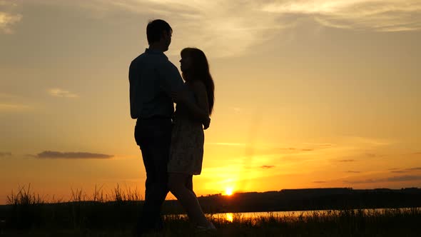 Loving Man and Woman Dance in Bright Rays of Sun on the Background of the Lake. Young Couple Dancing