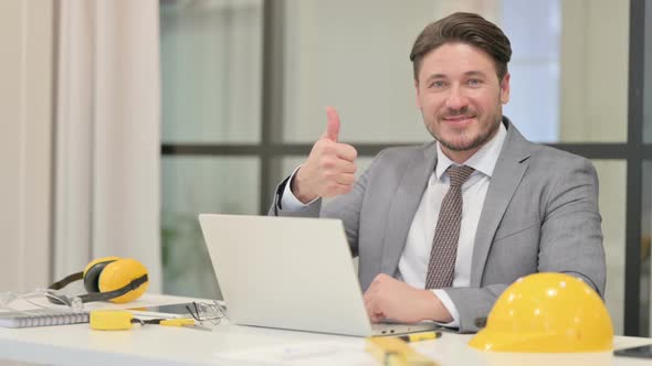 Middle Aged Engineer Showing Thumbs Up Sign While using Laptop in Office