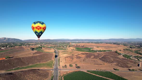 Flying by a hot air balloon floating over the Temecula vineyards in Southern California, aerial