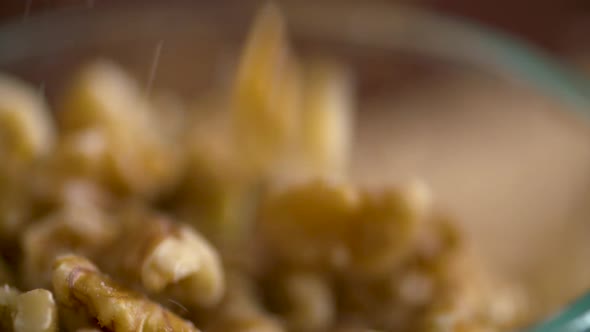 Slow motion footage of walnut pieces falling into a dish
