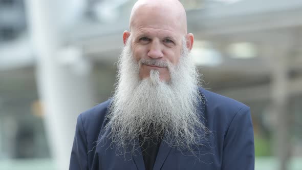 Face of Happy Mature Bearded Bald Businessman Smiling in the City Outdoors