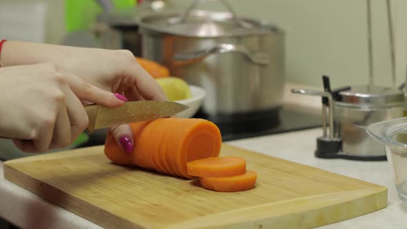 Female Housewife Hands Slicing Carrots Into Pieces in the Kitchen