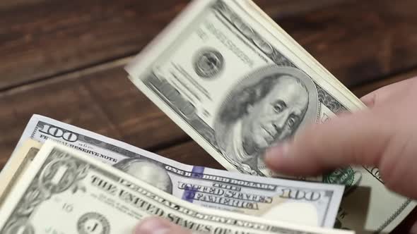 counting a pack of different dollar bills above the wooden table