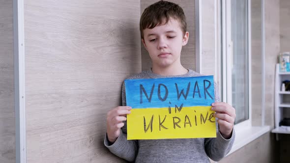 Child Holds in Hands a Banner with a Flag of Ukraine and Message No War