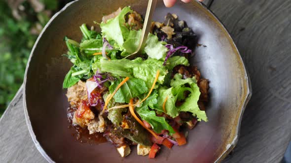 Top View of Fork Picking Up a Leaf From Salad Bowl and Showing It to the Camera