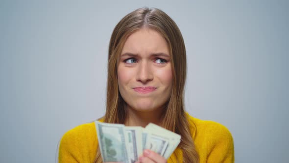 Portrait of Upset Woman Counting Money on Grey Background in Studio