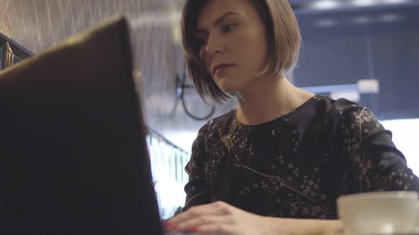 Woman Working on Her Laptop and Enjoying Her Coffee