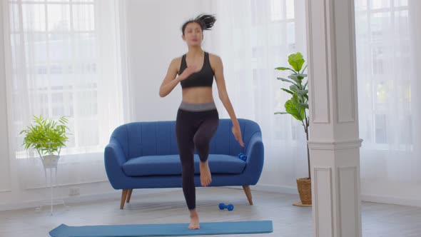 Athlete Asian young woman warm up running on exercise mat at home