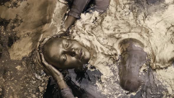 Golden Woman Is Diving Inside Water with Golden Shiny Metallic Pigment Top View Portrait