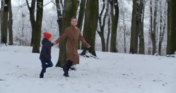 Mom With A Small Child Playing In A Snowy Park