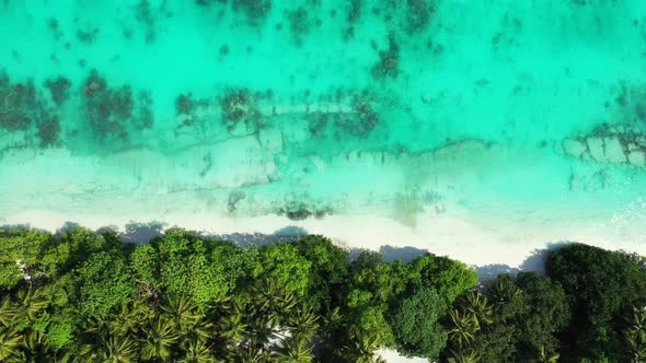 Wide overhead copy space shot of a white sandy paradise beach and blue ocean background in vibrant 4