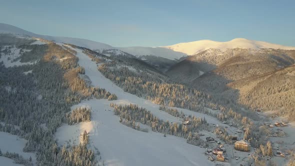 Flight Over a Village in Carpathian Mountains. Bird's Eye View of Snow-covered Houses in Mountains