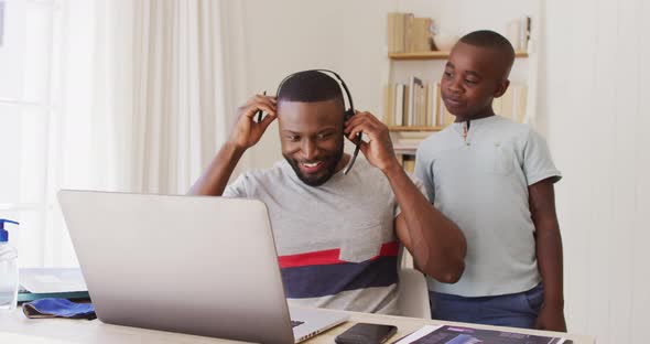 African american father  finishing video chat on laptop and talking to his son while working from ho