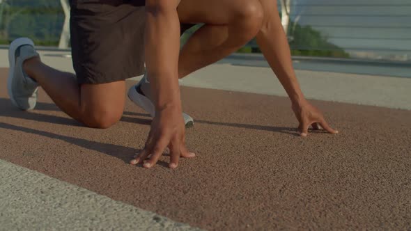 Closeup of African American Athlete Standing in Start Position on Running Track