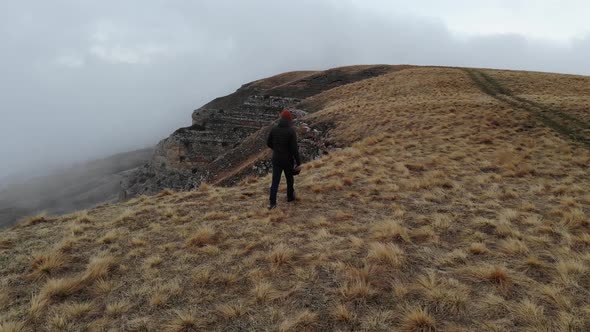 Tourist Traveler Man in Tourist Clothes Walks Along the Top of a Plateau Next to a Deep Cliff Along