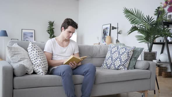 Penisve Young Man Reading Book at Work