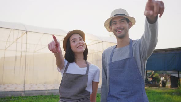 Happy two Asian couple farmers owner working in vegetables hydroponic greenhouse farm with happiness