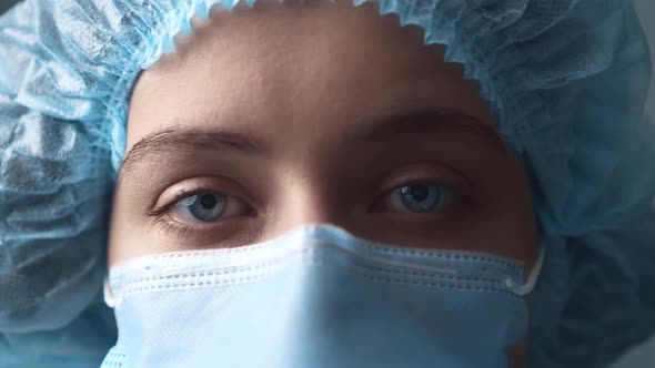 Eyes Of A Young Female Nurse In Front Of The Camera In A Surgical Mask And Cap. Protection Against