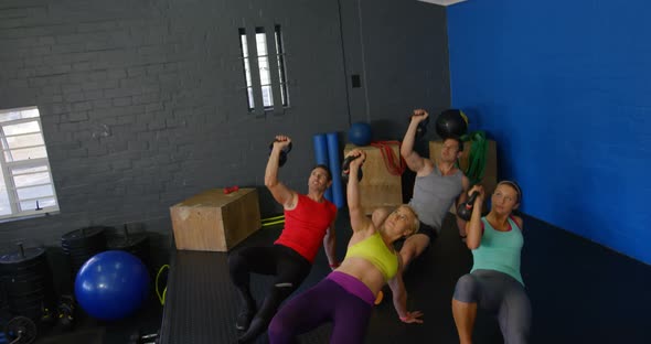 Group of people performing push-up with kettlebell