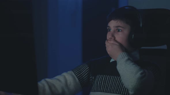 Scared Boy in Headphones Shocked By Terrible Scene While Watching Horror Video on Computer