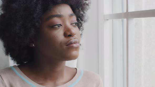 Thoughtful Lonely Millennial African Woman Look Through Window Alone at Home Feeling Anxious Hurt