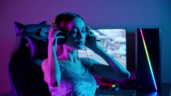 Tattooed Gamer Woman Sitting By the PC - Putting on Her Headphones and Starts Playing