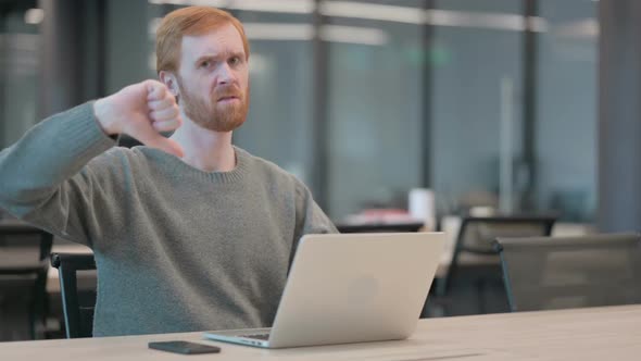 Young Man Showing Thumbs Down Sign While Using Laptop in Office