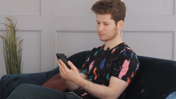 Man with a Phone at Home, Reading a Message on a Smartphone.