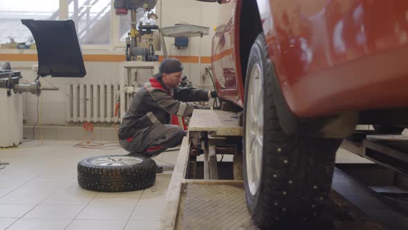 Mechanic Changing Tire of Car in Repair Shop